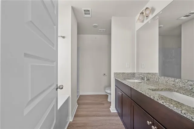a bathroom with a granite countertop sink a mirror and a shower