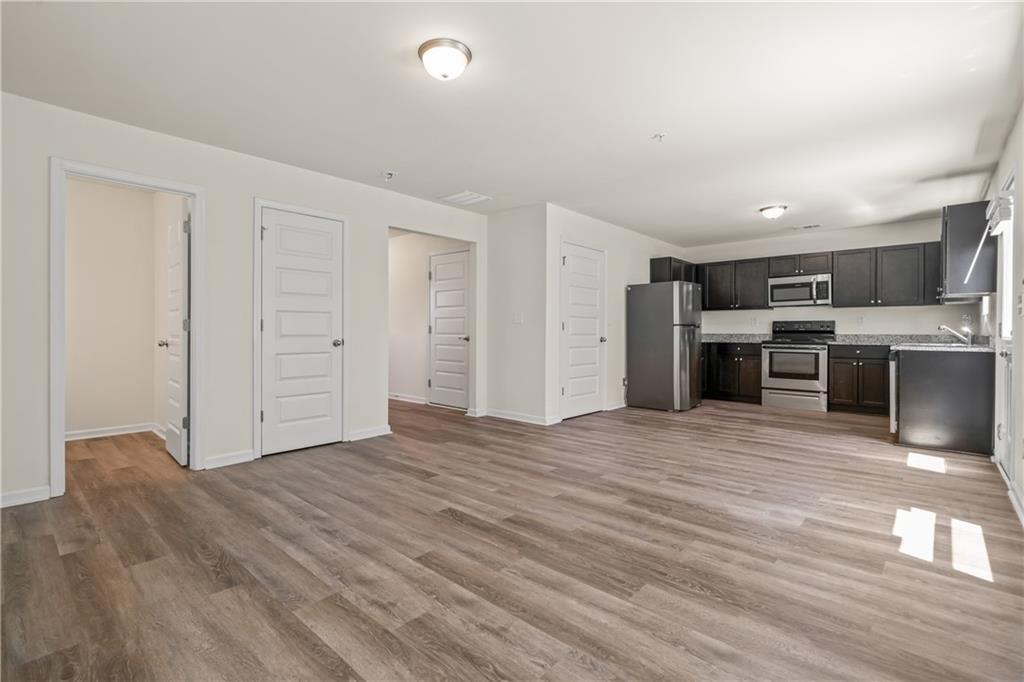 631 Carlton Pointe Drive, Unit 24 Palmetto, GA 30268 - Photo 6 of 20 an empty room with wooden floor and kitchen view