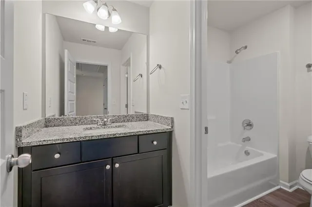 a bathroom with a granite countertop sink a mirror a vanity and a bathtub