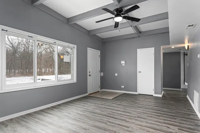 a view of an empty room with a window and wooden floor