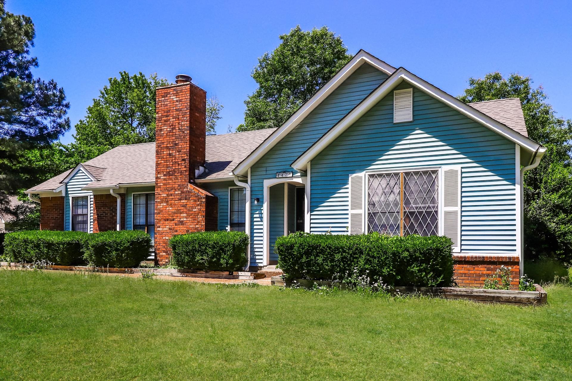 Bungalow featuring a front lawn, brick siding, a chimney, and a shingled roof