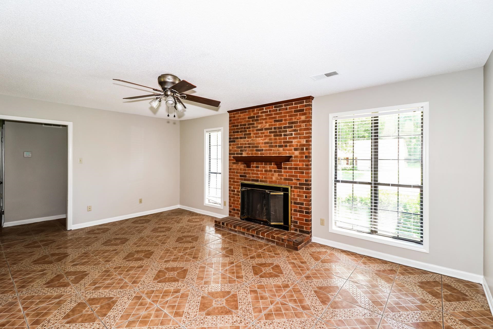 4475 Window Drive Memphis, TN 38135 - Photo 5 of 16 Unfurnished living room featuring ceiling fan, plenty of natural light, a brick fireplace, and light tile patterned flooring