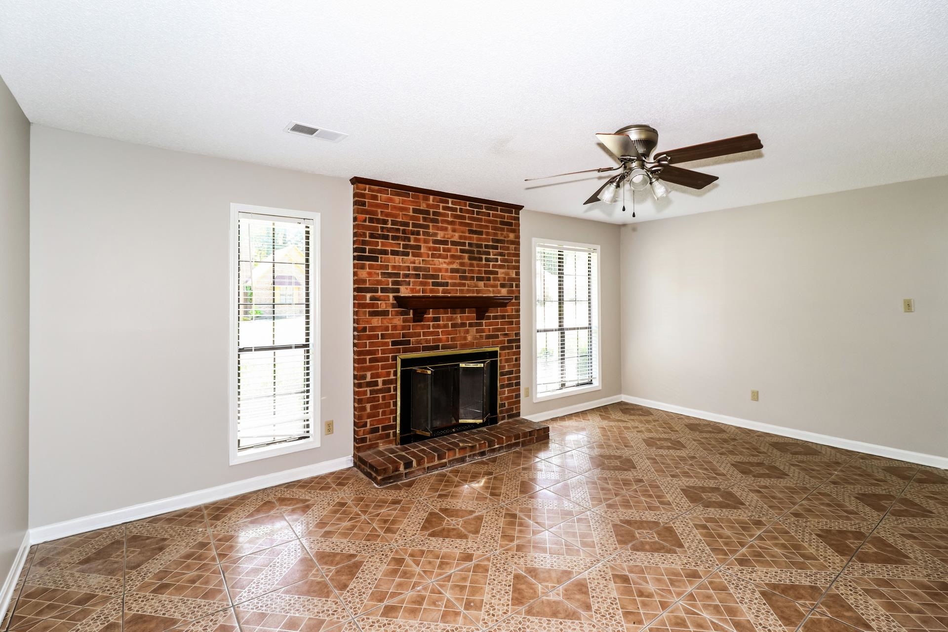 4475 Window Drive Memphis, TN 38135 - Photo 6 of 16 Unfurnished living room with a fireplace, ceiling fan, and light tile patterned floors