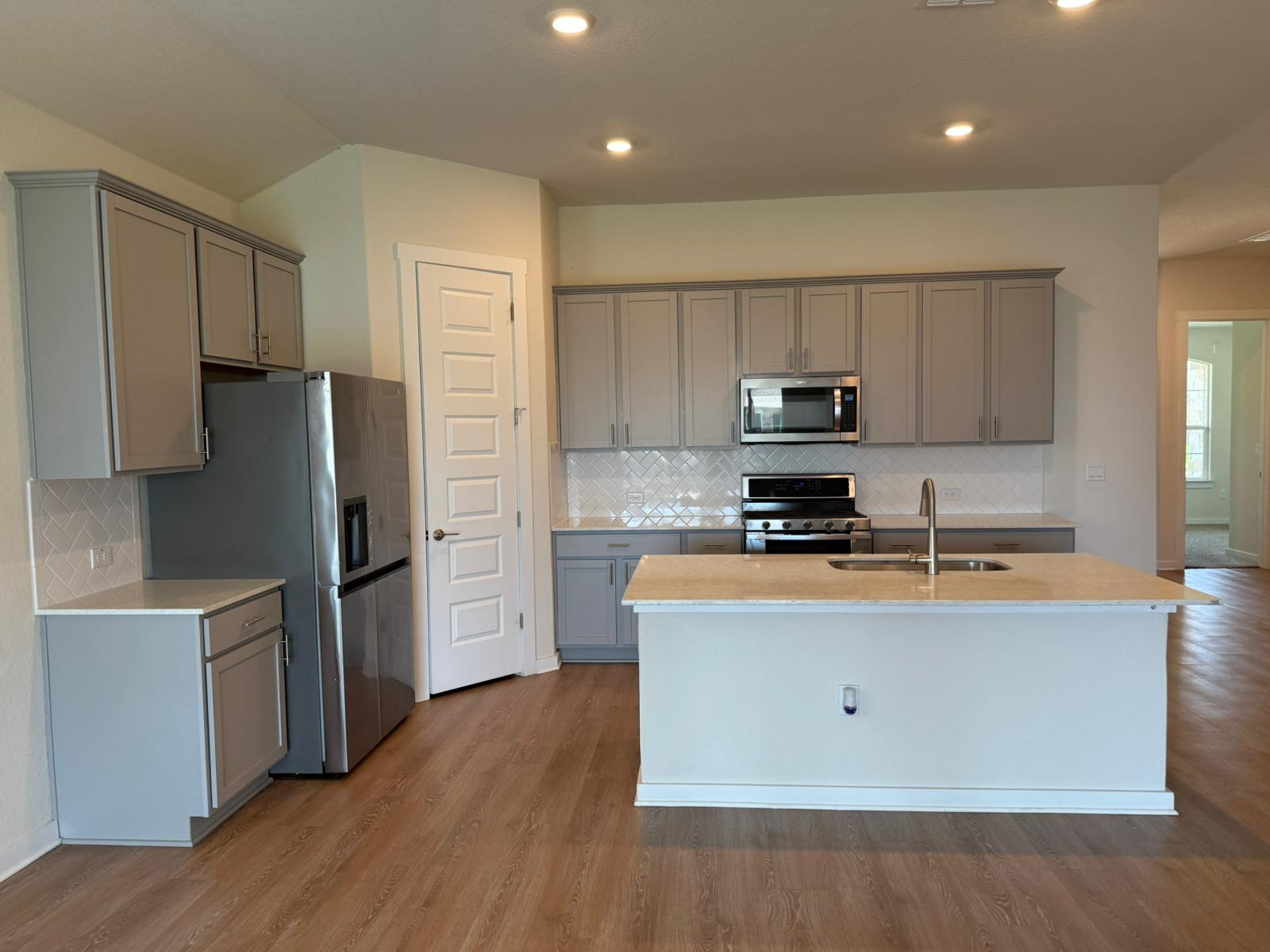 2037 Saddlery Street Leander, TX 78641 - Photo 17 of 38 a kitchen with stainless steel appliances granite countertop a stove a refrigerator a sink a microwave and wooden floor