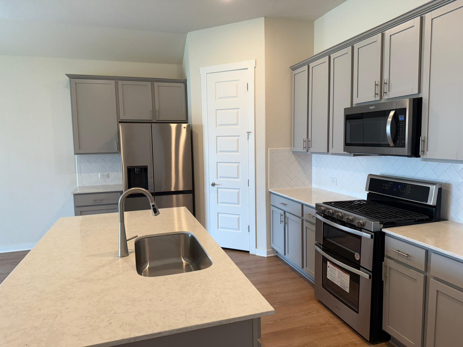 2037 Saddlery Street Leander, TX 78641 - Photo 19 of 38 a kitchen with stainless steel appliances a stove sink microwave and refrigerator