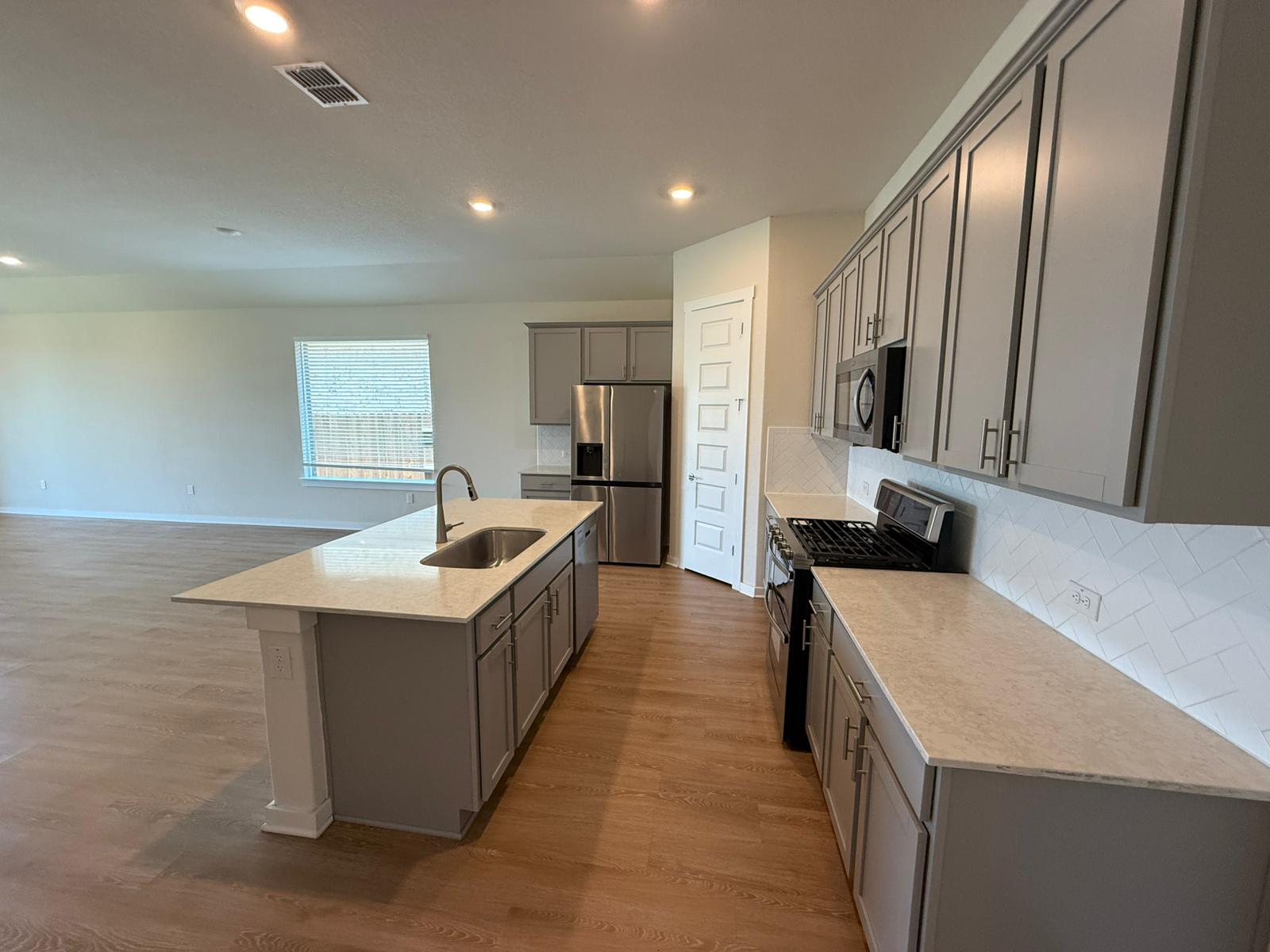 2037 Saddlery Street Leander, TX 78641 - Photo 23 of 38 a large kitchen with stainless steel appliances granite countertop a sink stove and refrigerator