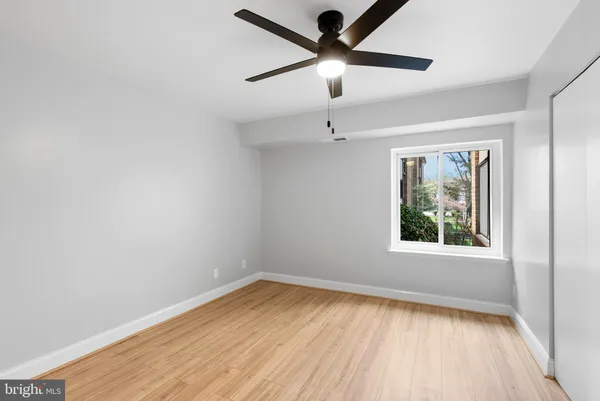 an empty room with a window and a ceiling fan