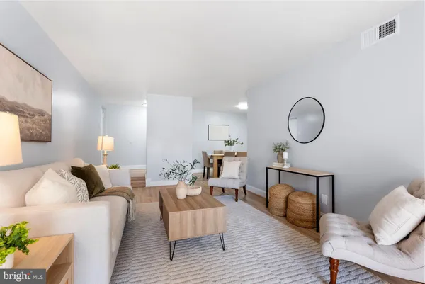 a living room with furniture a mirror and a wooden floor