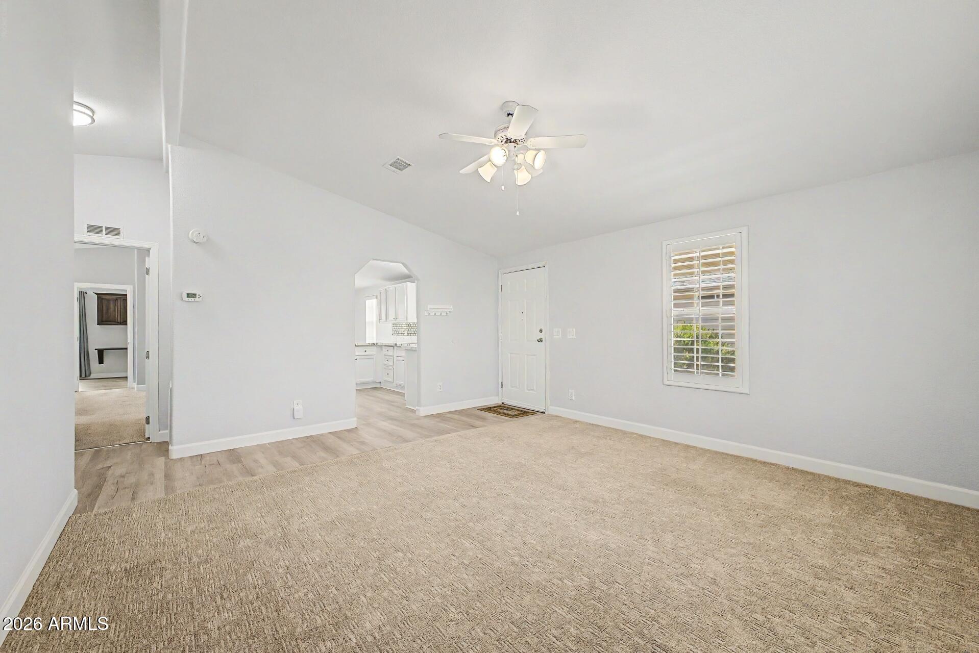 2550 South Ellsworth Road, Unit 50 Mesa, AZ 85209 - Photo 13 of 45 an empty room with chandelier fan and windows