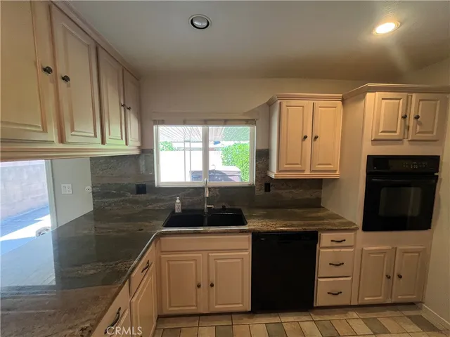 a kitchen with granite countertop a sink stove and cabinets