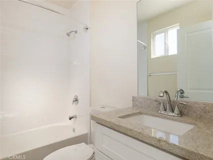 a bathroom with a granite countertop sink a toilet and bathtub