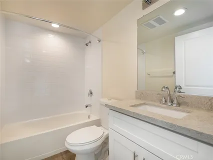 a bathroom with a granite countertop sink a toilet and shower