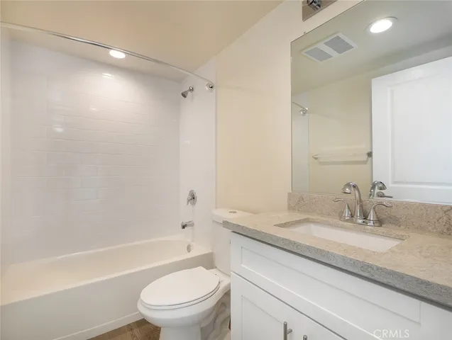 a bathroom with a granite countertop sink a toilet and shower