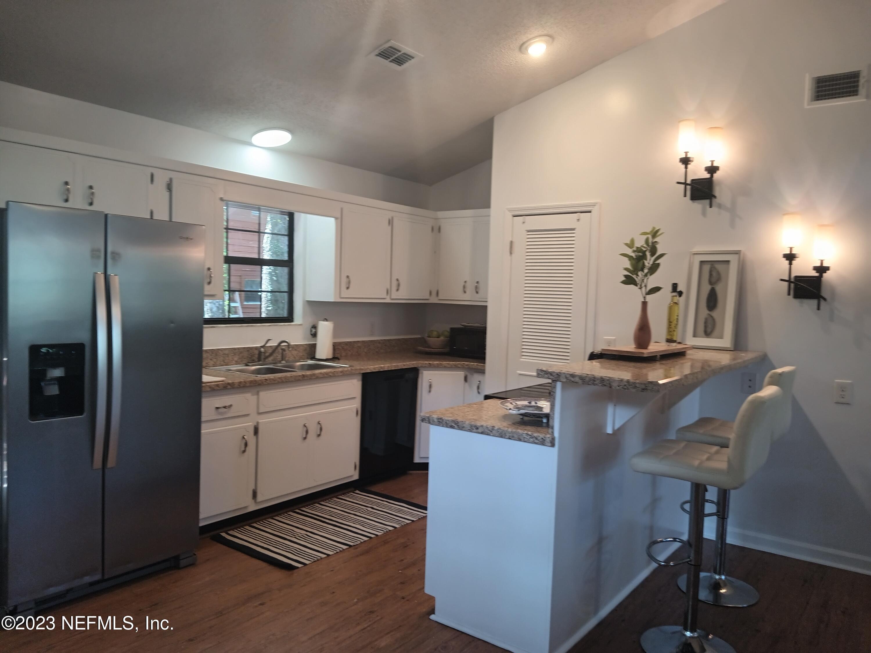 97612 Pirates Point Road Yulee, FL 32097 - Photo 12 of 23 a kitchen with kitchen island granite countertop a sink cabinets and stainless steel appliances
