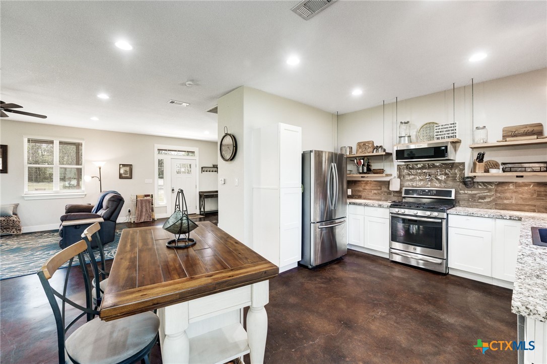 469 Whispering Oaks Loop Killeen, TX 76549 - Photo 11 of 48 a kitchen with stainless steel appliances a stove a sink a refrigerator white cabinets a dining table and chairs