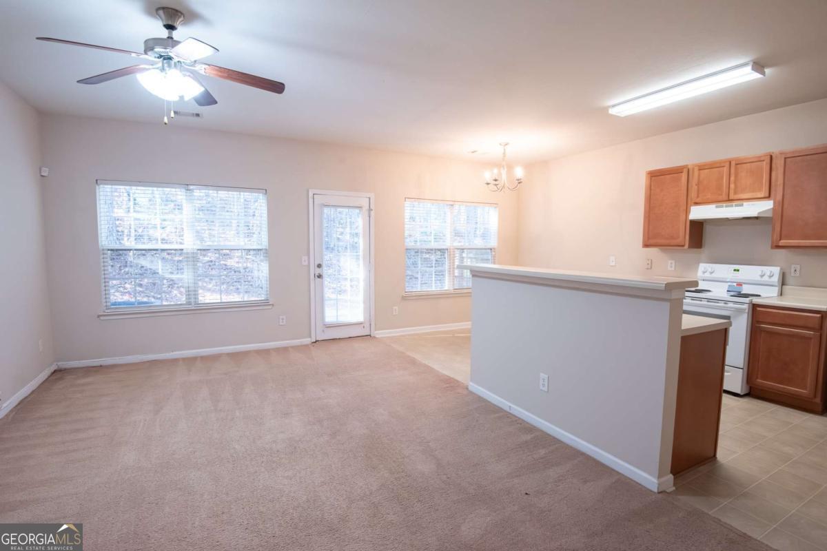 1259 Chinon Point Lithonia, GA 30058 - Photo 9 of 27 a view of a kitchen with a stove cabinets a ceiling fan and wooden floor