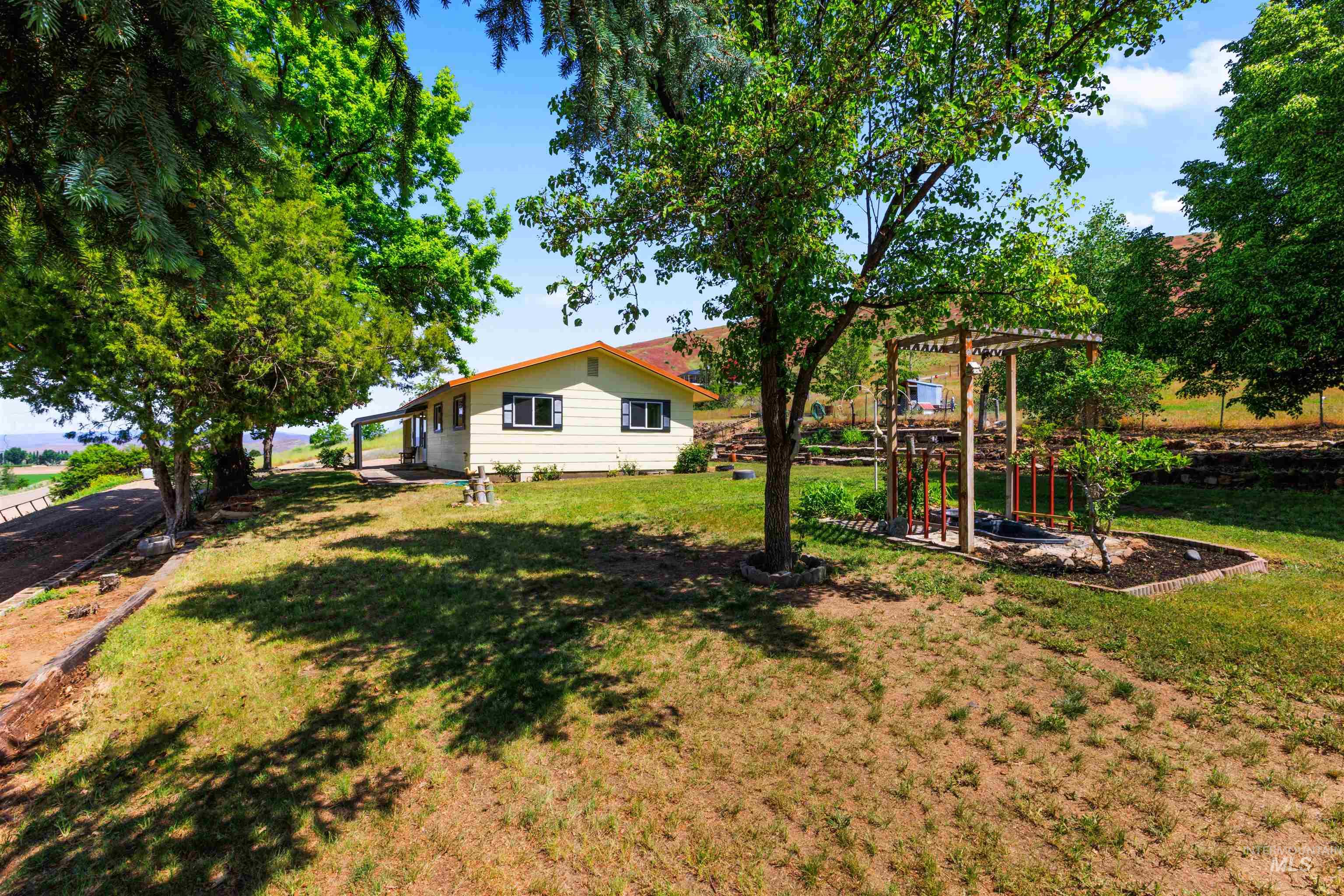 12184 Hill Road Payette, ID 83661 - Photo 8 of 35 Expansive outdoor area featuring a pergola with a built-in fire pit, mature trees, and a terraced landscape