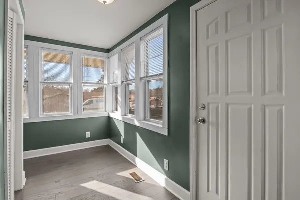 a view of an empty room with window and wooden floor