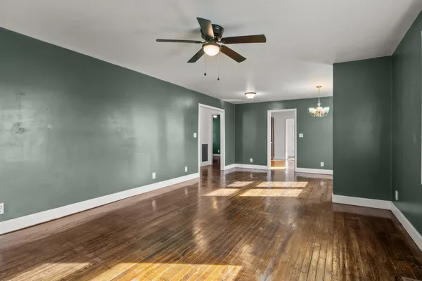 a view of an empty room with window and wooden floor