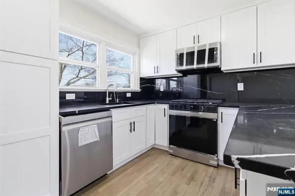 a kitchen with stainless steel appliances granite countertop a stove a sink and a microwave