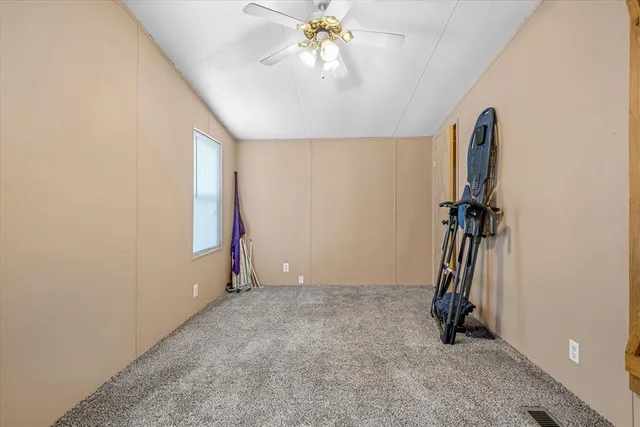 an empty room with chandelier fan and windows