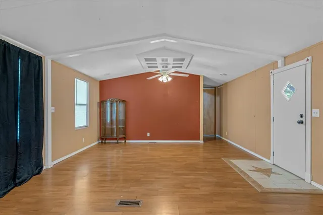 a view of an empty room with window and wooden floor