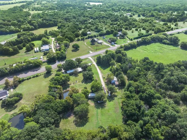 an aerial view of residential houses with outdoor space and trees