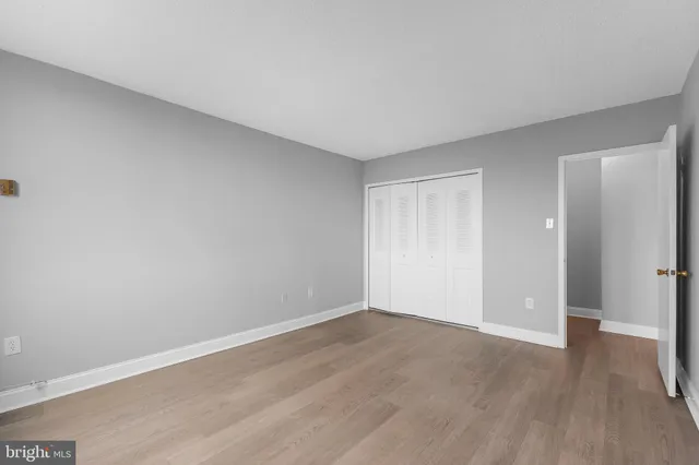 a view of an empty room with wooden floor and closet