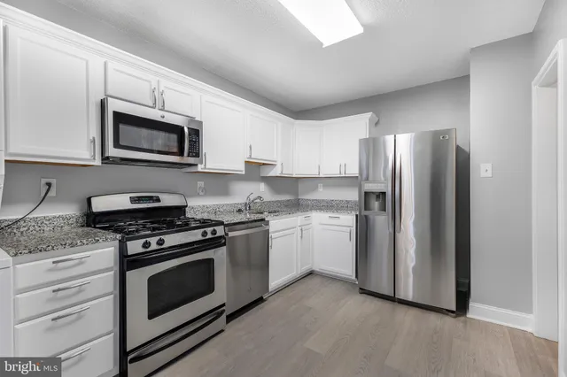 a kitchen with stainless steel appliances granite countertop a stove microwave and refrigerator