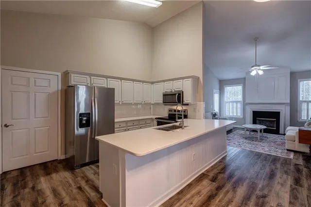 a large kitchen with a refrigerator a stove a sink dishwasher a dining table and chairs with wooden floor