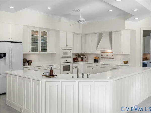 a kitchen with stainless steel appliances white cabinets a sink a stove a refrigerator and a refrigerator