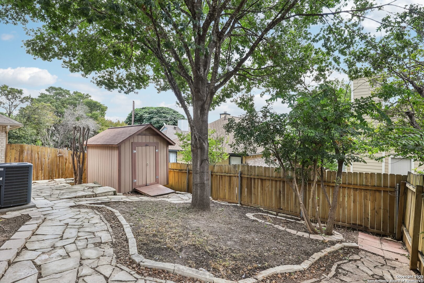 5834 Spring Crossing San Antonio, TX 78247 - Photo 25 of 29 a front view of a house with a large tree and wooden fence