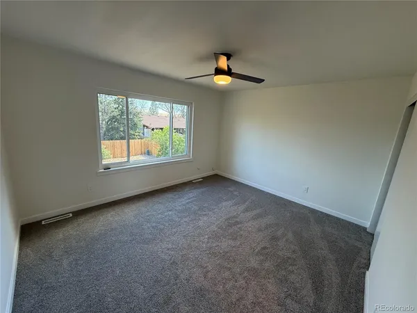 an empty room with windows and ceiling fan