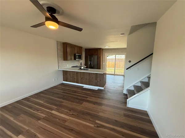 a view of kitchen and empty room with wooden floor