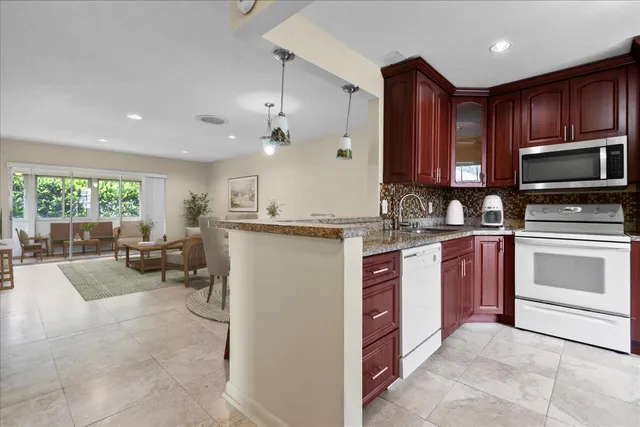 a kitchen with kitchen island granite countertop wooden cabinets a stove a sink and a oven with wooden floor