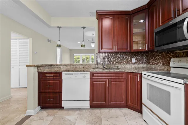 a kitchen with stainless steel appliances granite countertop wooden cabinets and a stove top oven