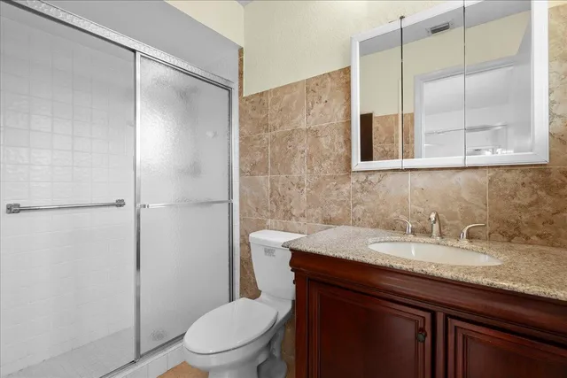 a bathroom with a granite countertop sink toilet and shower