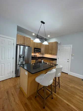 a kitchen with granite countertop a table chairs stove and refrigerator