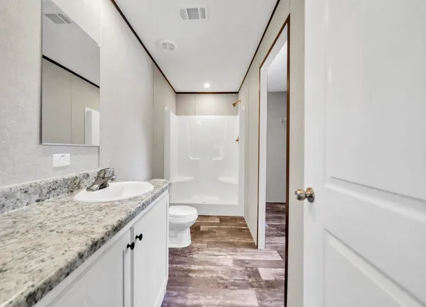 a bathroom with a granite countertop sink a toilet and shower