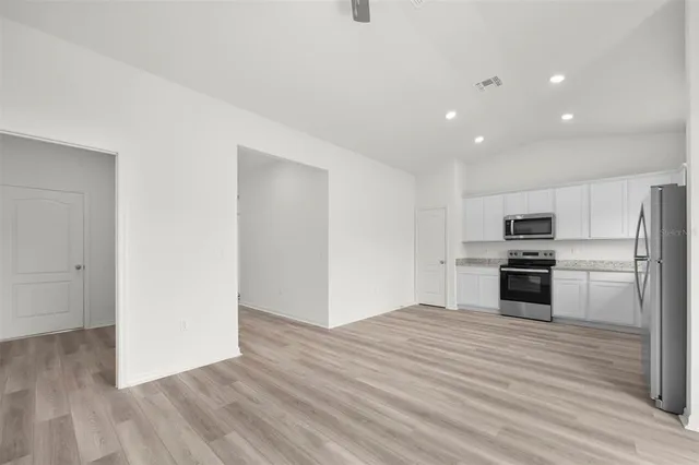 a kitchen with granite countertop a refrigerator and a stove top oven