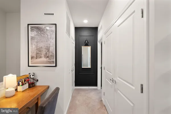 a bedroom with a bed a mirror on desk and a large window
