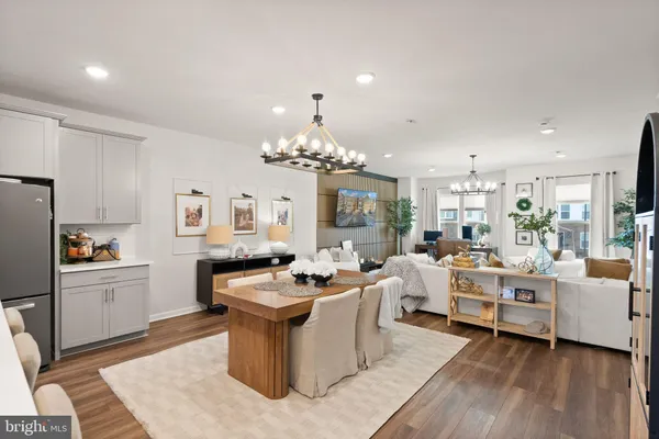 a kitchen with stainless steel appliances granite countertop a dining table chairs refrigerator and microwave