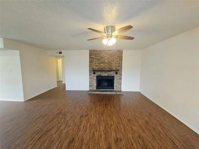 a view of empty room with wooden floor and fireplace