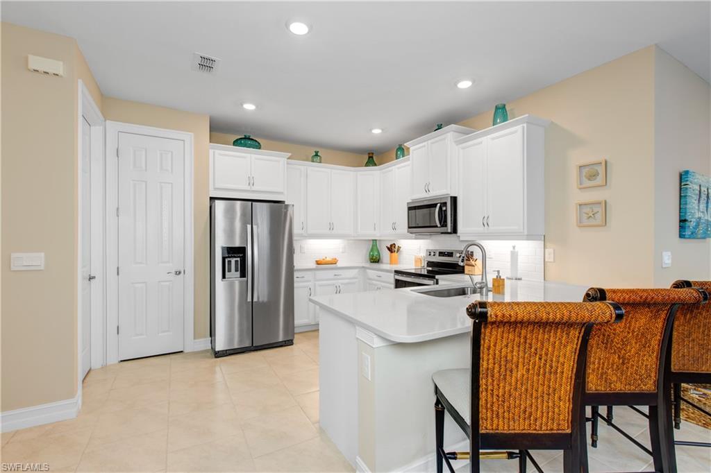 846 Enbrook Loop Naples, FL 34114 - Photo 6 of 45 a kitchen with stainless steel appliances granite countertop a refrigerator a stove top oven a sink a stove a dining table and chairs