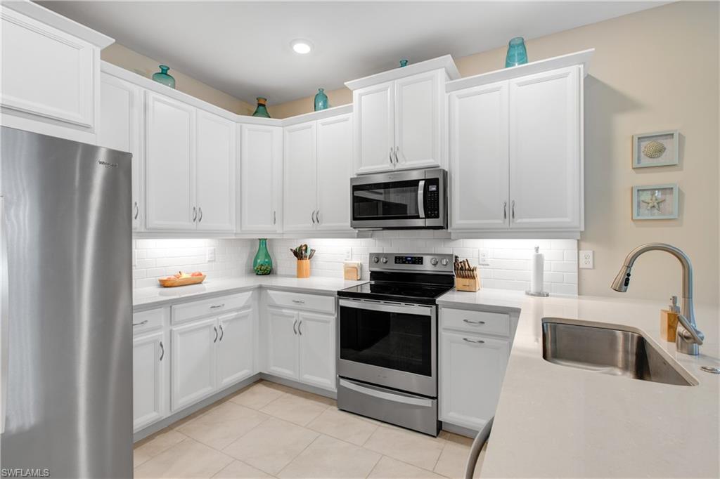 846 Enbrook Loop Naples, FL 34114 - Photo 7 of 45 a kitchen with white cabinets a sink and white appliances