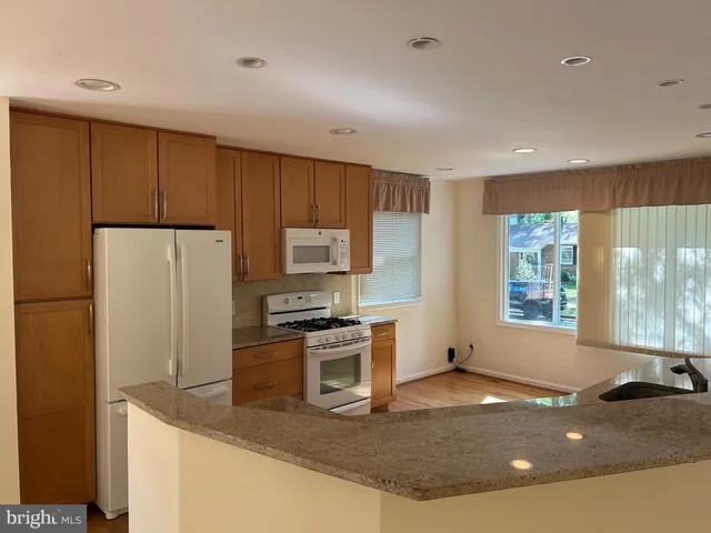 a kitchen with stainless steel appliances granite countertop a sink a stove a refrigerator a counter top space and cabinets