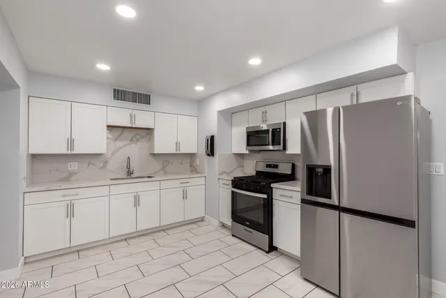 a kitchen with stainless steel appliances granite countertop a refrigerator sink and stove