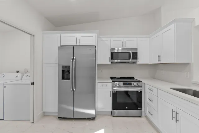 a kitchen with white cabinets and stainless steel appliances