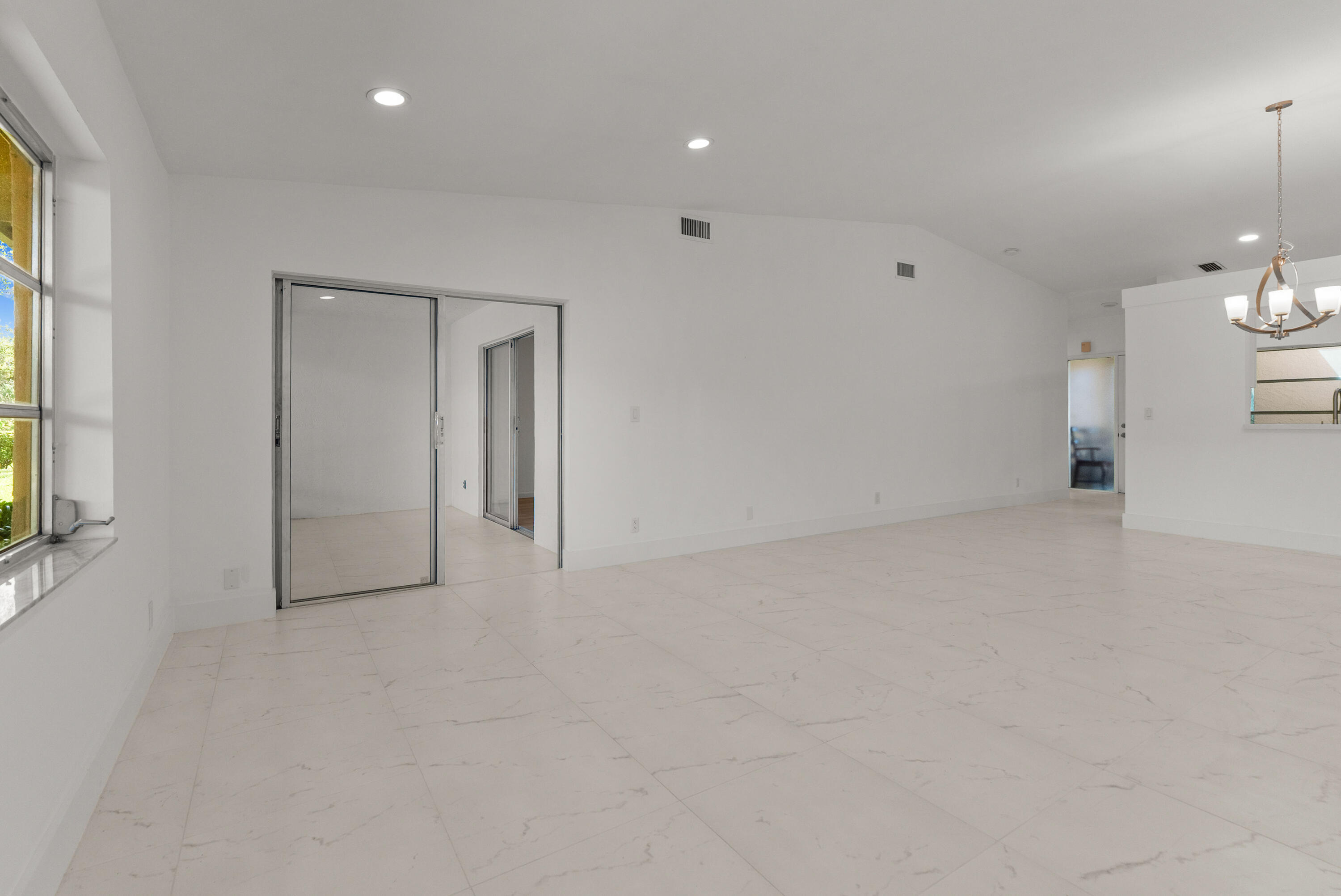 8273 Springtree Road Boca Raton, FL 33496 - Photo 19 of 35 an empty room with chandelier fan and windows
