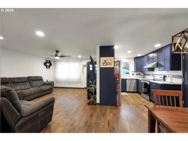 a living room with stainless steel appliances furniture and kitchen view